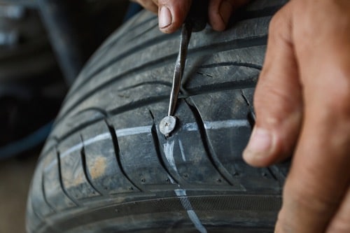 Tires and Alignments: A nail is shown being removed from a tire for tire repairs at Bock Automotive