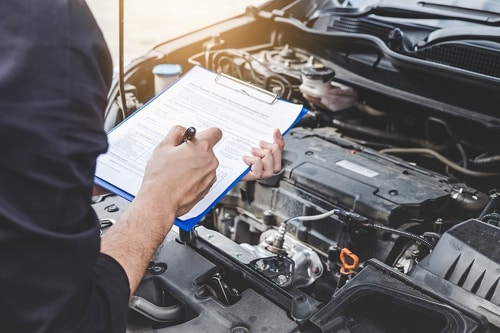 5 things your mechanic looks for when inspecting a vehicle; Bock Auto Amagansett Ny Mechanic marking off on a paper inspection on a clipboard while standing over car engine