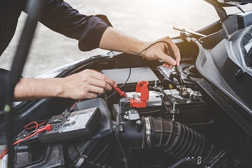 How to Tell If a BMW Battery or Alternator Needs Replacing Services in Hamptons, NY. Image of an auto mechanic repairman checking car engine battery in an automotive workshop.