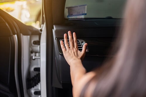 Why is My Car A/C Blowing Out Warm Air? | Bock Auto in Amagansett, NY. Close up image of a hand of a woman checking flow of cold from air conditioner in modern car.
