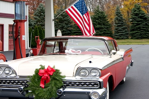 Classic Car Maintenance Tips for Winter | Bock Auto, Amagansett, NY. Image of mid 1950’s classic car at gasoline station with Christmas wreath on the front hood.