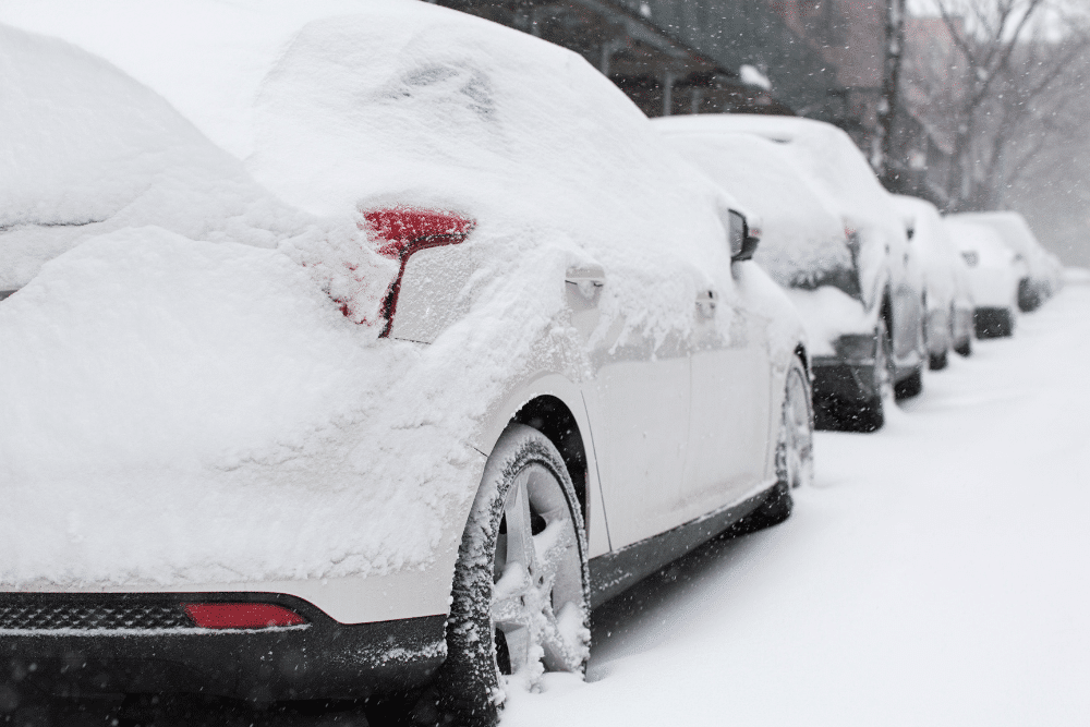 Winter car prep, auto repair in Amagansett, NY by Bock Auto. Image of vehicles covered in heavy snow along a roadside. Highlighting Bock Auto’s commitment to helping drivers stay safe and prepared for harsh winter conditions.